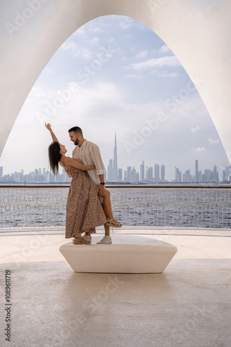 Young couple in love visiting Dubai with the backdrop of the city skyline as they enjoy holding each other close.