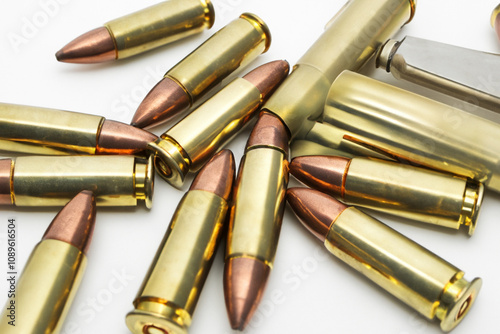 A bullet sitting on top of a white surface. A black and white background with gray gold bullets. Gold bullets gray background shooting. A shot of a gray lifestyle background shooting bullets.