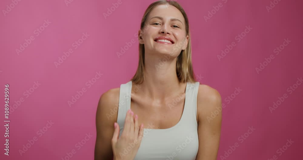 A woman smiles looking at the camera standing on a studio background. She adjusts her hair A woman smiles looking at the camera standing on a studio background. She adjusts her hair