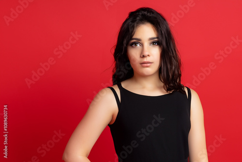 A woman in a black dress posing against a red background. A girl in a red dress with a red background. Girl dress red background holiday black. A black and red dress with a lifestyle red background.