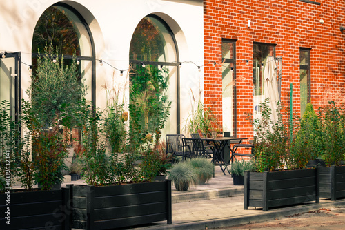 Europe street exterior urban view restaurant patio gardening space road landscaped city summer environment space old building style plant pots along red brick and arch windows