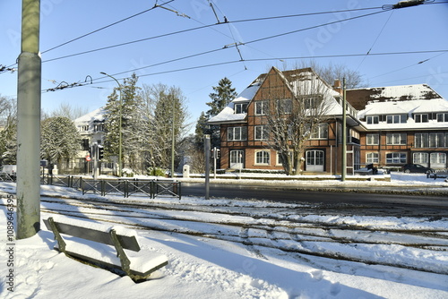 Banc en face de la ligne de tram et un bâtiment de bureaux sous la neige à l'avenue de Tervuren à Bruxelles  photo