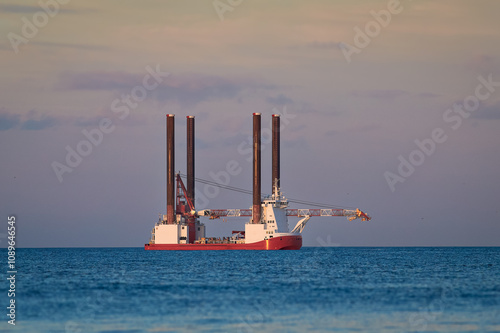 Jack up wind turbines installation vessel in the sea, with beautiful colourful sky. photo