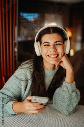 Young caucasian woman enjoying music on wireless headphones at home	 photo