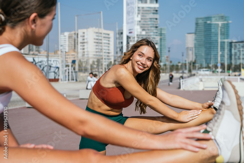 Two young women stretching together after an outdoor workout in barcelona