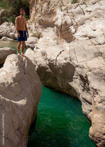 Man Jumping into Turquoise Waters at Wadi Bani Khalid photo