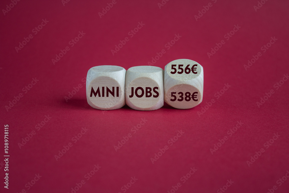 Cubes with symbol for the raise of the income limit for tax free 'mini jobs' in Germany from 538 Euro to 556 Euro in 2025. Beautiful red background. Business concept.