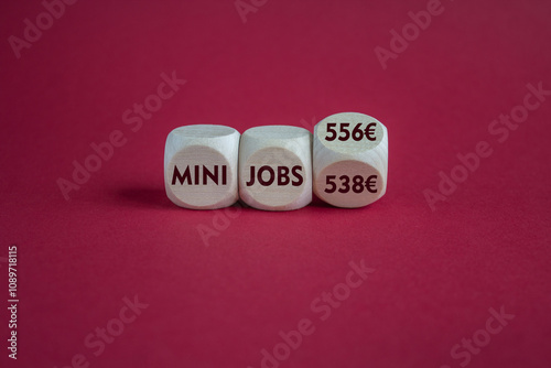 Obraz na płótnie Cubes with symbol for the raise of the income limit for tax free 'mini jobs' in Germany from 538 Euro to 556 Euro in 2025. Beautiful red background. Business concept. w salonie