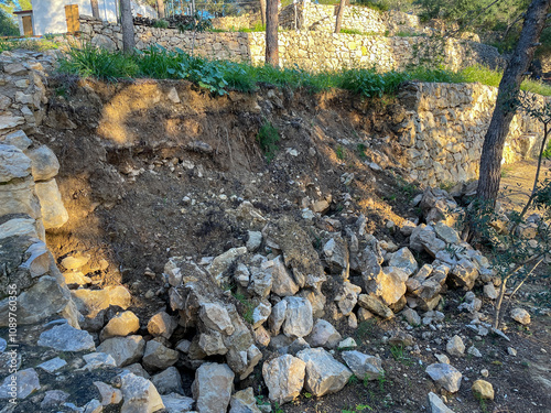 Collapsed stone retaining wall with scattered rubble