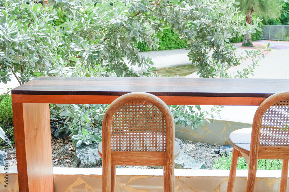 Obraz premium Wicker chair and wooden table in restaurant,Rattan chair in scandinavian interior of living room,Mediterranean minimal wall and green plant exterior architecturer,warm beige tones,copy space.