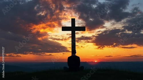 Man Sitting and Praying Near Cross at Sunset