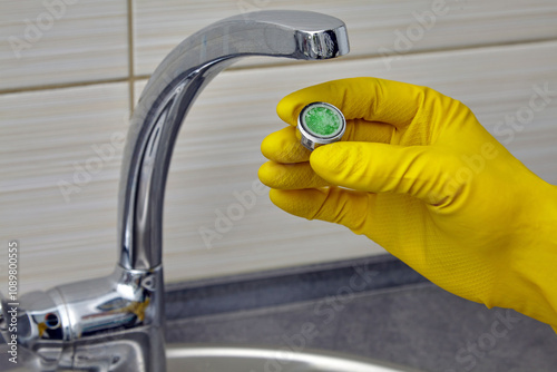 person in yellow rubber gloves changing clogged faucet aerator