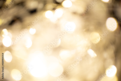 Golden brown Christmas bokeh background. Blurred white garland lights background with glitters and soft reflections for rendering, greeting cards and postcards. Blurry vintage gold abstraction.