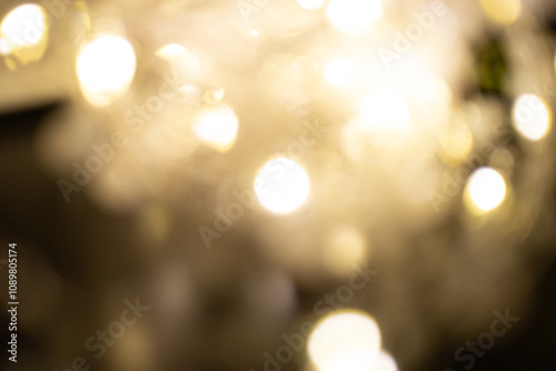 Golden brown Christmas bokeh background. Blurred white garland lights background with glitters and soft reflections for rendering, greeting cards and postcards. Blurry vintage gold abstraction.