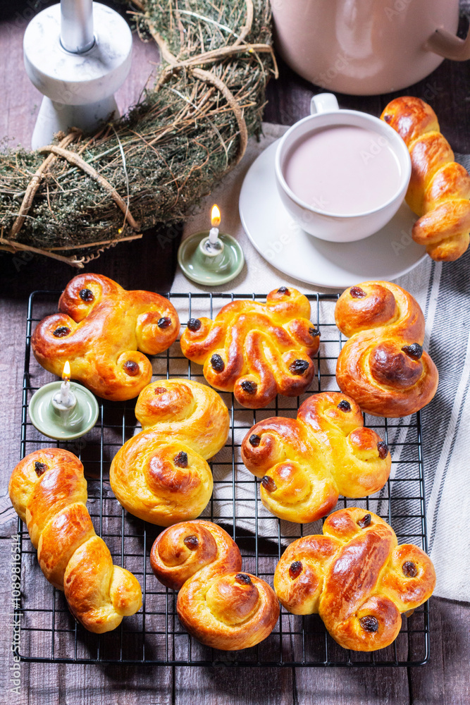 Traditional saffron Swedish buns lussekatt in different shapes, served with cocoa on a wooden table. Buns for St. Lucia's Day.
