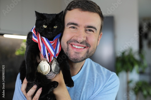 Man holding a cat that has won several medals  photo