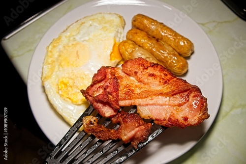 A white plate with Bacon sausage and eggs, a lovely keto carnivore diet for breakfast.