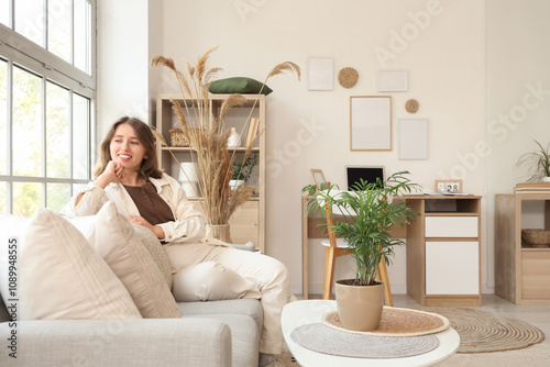 Young woman sitting on sofa...
