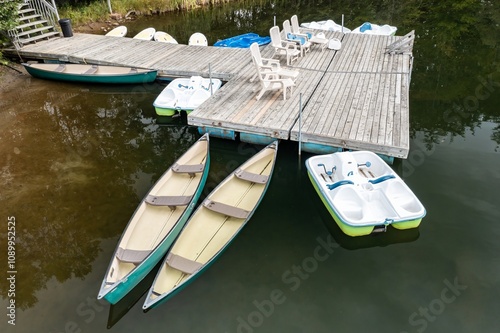 Pontoon and canoes moored on a calm lake in Lac Moore, Mont-Tremblant, Quebec, Canada.