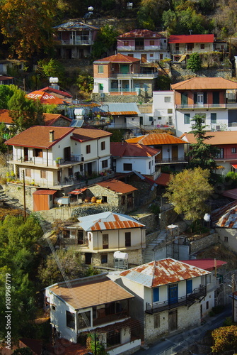 A scenic view of Moutoullas village in Cyprus, featuring traditional stone houses with colorful rooftops nestled on a hillside, surrounded by lush greenery and showcasing rustic Mediterranean charm. photo