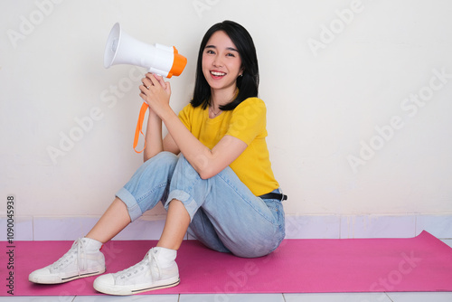 A woman sitting on the floor holding megaphone with excited expression photo