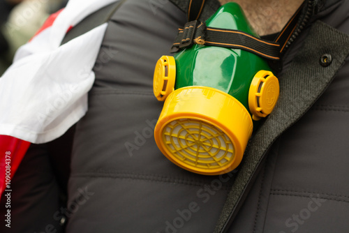 Tbilisi, Georgia - November 19, 2024: Yellow green respirator on neck of man with Georgian flag close up. Photo. Peaceful protest of townspeople and city citizens against parliament election results photo