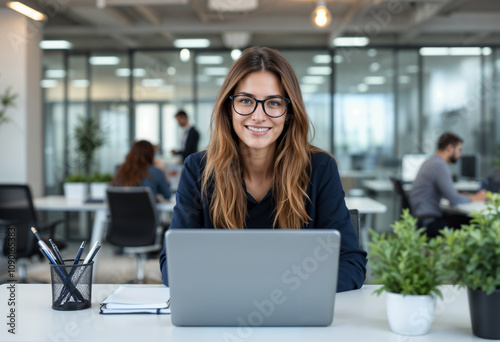 A talented businesswoman with glasses sits at a desk in a modern office environment, smiling confidently at the camera Free Download A talented businesswoman with glasses sits at a desk in a modern office environment, smiling confidently at the camera - GFXLoad