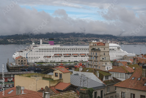 Classic British cruiseship cruise ship liner Ambience docked at pier terminal in port of Vigo, Spain in Galicia during summer Atlantic Coast cruising with sky, clouds and coast line