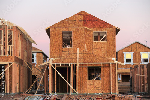 Wooden structures of tract homes at various stages of construction in a new subdivision