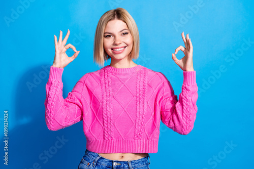 Photo of pretty young woman show okey symbol wear pink pullover isolated on blue color background