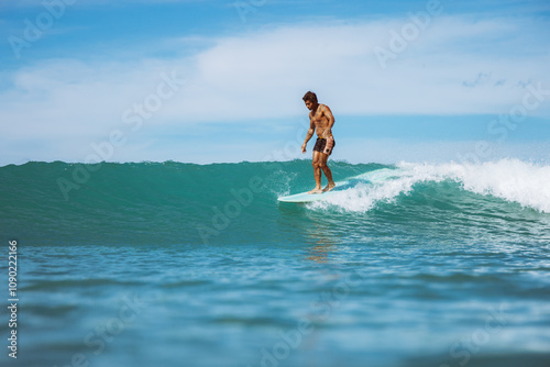 Photography A man is surfing on a wave in the ocean
