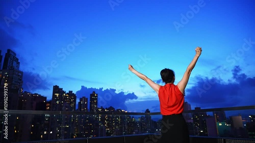 Businesswoman standing on the rooftop with arms up