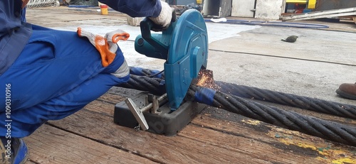 Worker cutting a huge steel wire on a construction site, creating sparks but maintaining safety. Hot work background.