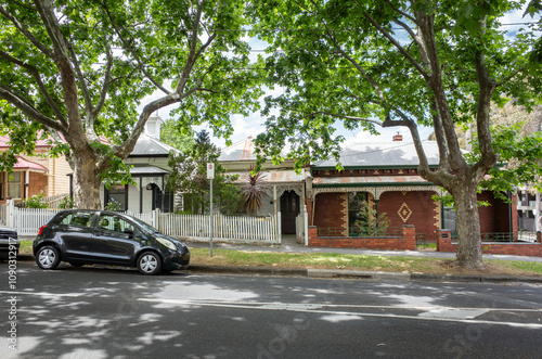 Historic Australian streetscape featuring traditional Victorian-style houses and a leafy canopy of mature green trees lining the suburban road. Heritage ambiance and beautiful environment in Australia photo