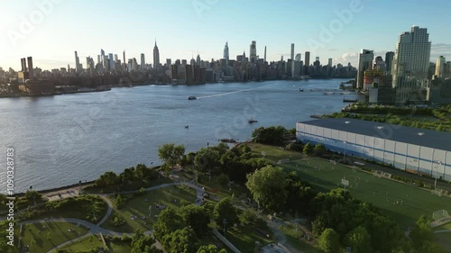 A beautiful horizontal drone rise shot over Bushwick Inlet Park in Williamsburg, Brooklyn, gradually revealing the park, East River, and the surrounding cityscape in a breathtaking aerial view. photo