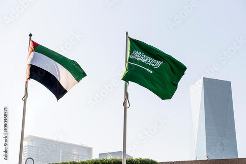 flags of Saudi Arabia and United Arab Emirates against the background of a tall building,