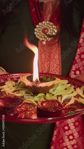 Vertical shot of unrecognizable woman holding plate with burning diya while celebrating Diwali photo