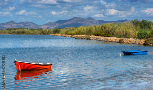 pretty red boat moored in the sea in Sardinia with mountain  in background un...