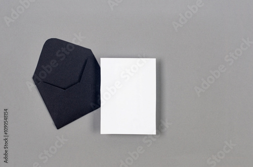 Black envelope with empty white card for text on grey background