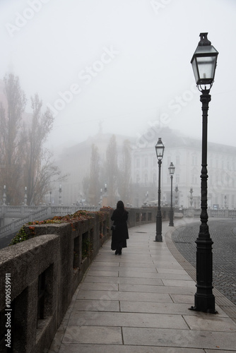 Mysterious Woman walking alone on a foggy bridge in ljubljana photo