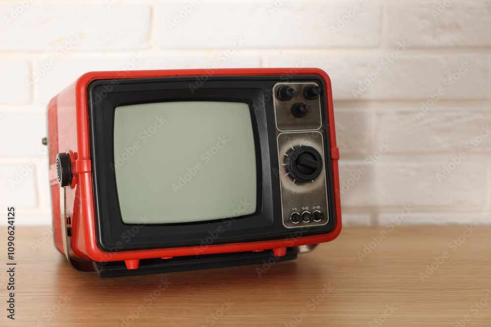 Obraz premium Retro tv set on wooden shelf against white brick wall