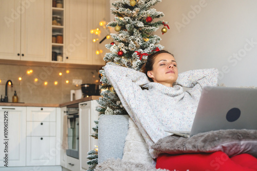 Woman with eyes closed and hands behind head relaxing on sofa during Christmas holidays.  photo