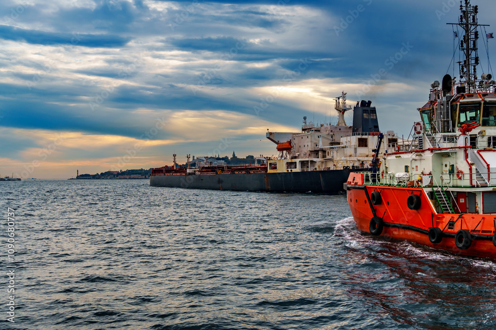 Fototapeta premium A large tanker ship and tug boat sails along the Bosphorus against the background of Istanbul, Turkey, a view from a pleasure boat