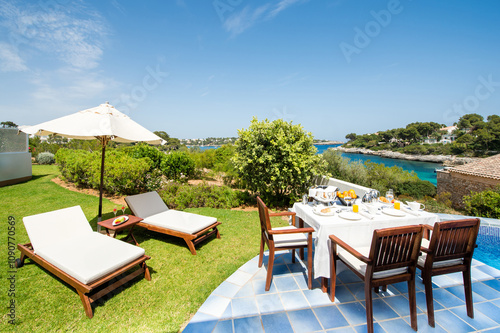 Serene coastal terrace with relaxation and dining setup photo