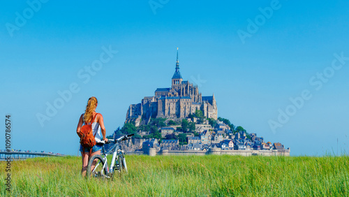Obraz na płótnie Abbey Mont Saint-Michel, Normandy in France, female tourist in bicycle looking at the view w salonie