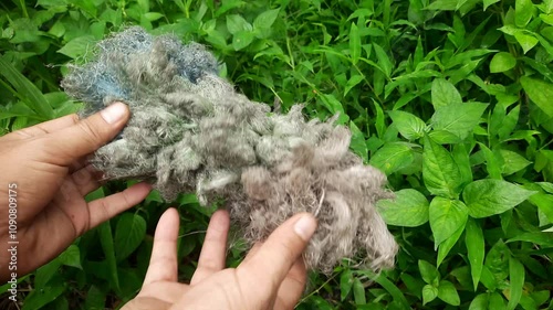 A man holds a dirty and dull plastic feather duster