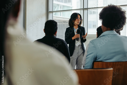 Businesswoman presenting in modern office to coworkers during a meeting photo