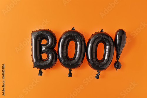 Black balloons spell boo against a bright orange background for Halloween