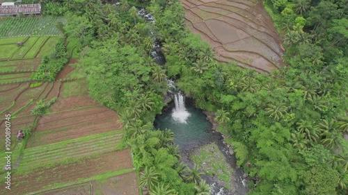 An aerial view of Penisihan Waterfall in Purbalingga, Central Java, Indonesia. The video showcases the stunning natural beauty and serene surroundings of the waterfall. photo