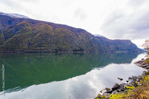 Autumn landscape in Lustrafjorden, South Norway, featuring clear water reflections, mountains, and colorful foliage. photo